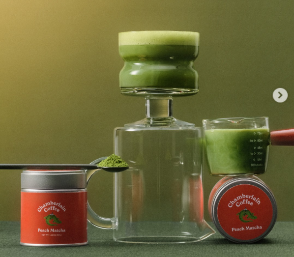 Chamberlain Coffee Peach Matcha ceremonial-grade matcha displayed in aesthetic glassware with creamy green foam, vibrant matcha powder, and cozy café-style vibes.