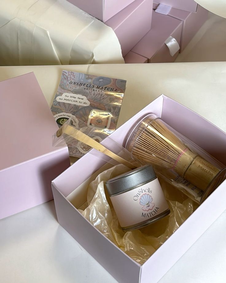Pastel pink OnShells Matcha ceremonial matcha set with matcha powder tin, bamboo whisk, scoop, and free stickers inside aesthetic gift packaging.